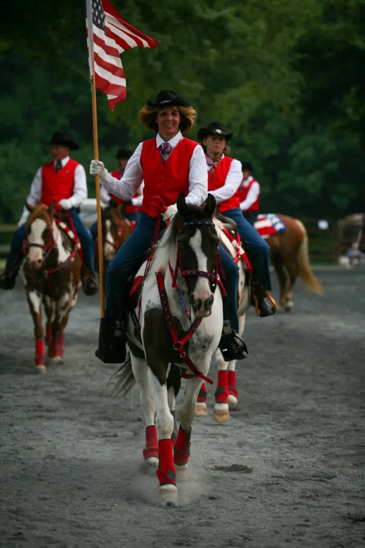 Women and men riding horses holding the flag